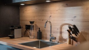 Una cocina moderna con un lavamanos de acero inoxidable, una cafetera y un bloque de cuchillos.