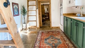 A loft-style room with a wooden staircase, a large rug, and a loft bed. - Cozy cabin in serene natural setting. Rustic charm with modern amenities! (Franklinton)