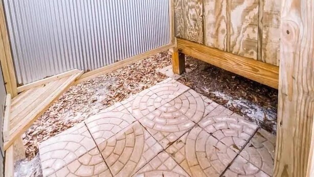 A wooden outdoor deck with a built-in bench and a small enclosed area with a door. - Cozy cabin in serene natural setting. Rustic charm with modern amenities! (Franklinton)
