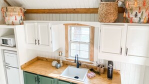 A kitchen with white cabinets, a wooden countertop, a window, and a microwave. - Cozy cabin in serene natural setting. Rustic charm with modern amenities! (Franklinton)