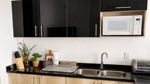 Uma cozinha moderna com armários pretos, uma pia de aço inoxidável, micro-ondas e fogão a gás.