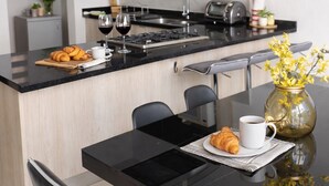Uma cozinha moderna com uma ilha central, uma mesa de jantar com cadeiras e um vaso com flores amarelas.