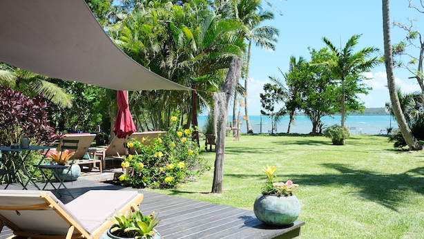 Une terrasse avec des chaises longues, une table et des plantes en pot.