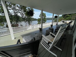 A covered deck with white railings, outdoor furniture, and hanging plants.
