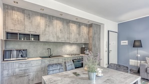 A modern kitchen with grey cabinets, a built-in microwave, and a dining area with a table and chairs. - Porto Letizia Paganini 4, Porlezza, Italy (Porlezza)