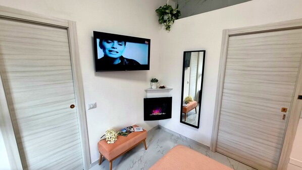 A modern bathroom with a TV mounted on the wall, a mirror, a bench, and a fireplace. - Casa Storica 5 Giornate (Milan)