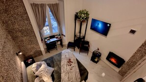 Une chambre d’hôtel moderne équipée d’un lit, d’un bureau, d’une télévision, d’une cheminée et d’une fenêtre avec des rideaux.