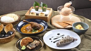 Variedad de platos que incluyen arroz, sopa y mariscos, dispuestas sobre una mesa de madera.