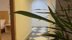 Un pasillo con una lámpara moderna, una planta y un suelo estampado.