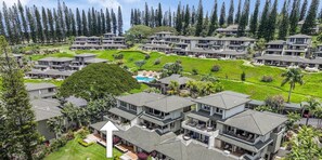 Vista aérea das Kapalua Golf Villas 17T8, mostrando edifícios modernos de vários andares, jardins bem cuidados e um campo de golfe.