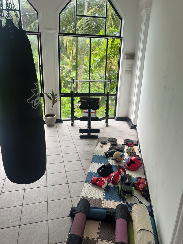 A gym area with a punching bag, exercise equipment, and various fitness accessories on a mat. - Hummus Hotel Hikkaduwa (Hikkaduwa)