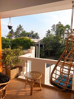A balcony with a wicker chair, a small table, and potted plants. - Hummus Hotel Hikkaduwa  (Hikkaduwa)