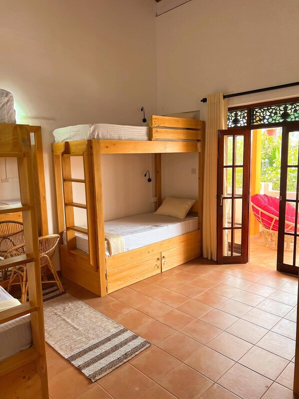 A bunk bed room with a desk and chair, a patterned rug, and a view of the outside.