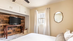 Ein Schlafzimmer mit einer Wandverkleidung aus Holz, einem Fernseher, einem großen Bett und einem Spiegel.