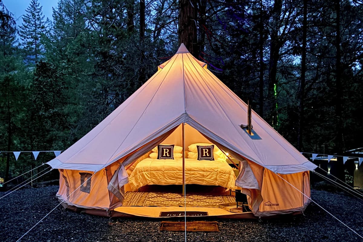 A tent with a triangular roof, a bed inside, and a letter 'R' on the bed.