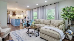 A modern living room with a sofa, a coffee table, and a dining area with chairs. - King Branch Rd · 3BR | Hot Tub | Dog Friendly | Wi-Fi | Games (Sevierville)