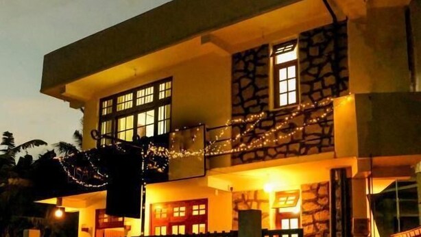 A two-story house with a stone facade, a gated entrance, and a staircase leading to the upper floor. - Cottage 23 (Kurunegala)