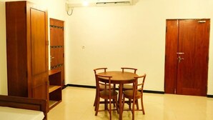 A room with a wooden wardrobe, a dining table with chairs, and a ceiling fan. - Cottage 23 (Kurunegala)