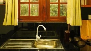 A kitchen with a double door window, a stainless steel sink, and wooden cabinets. - Cottage 23 (Kurunegala)