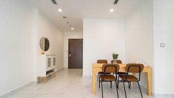 A dining area with a wooden table and four chairs, a white console with a mirror, and a door in the background.