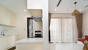 A modern kitchen with a built-in oven and a dining area with a red sofa and a vase of flowers.