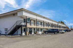 A multi-story motel with a covered entrance and a staircase leading to the parking area. - Pets are Welcome! w/ FREE Breakfast & Parking, Close to Peels Slough! (Montesano)