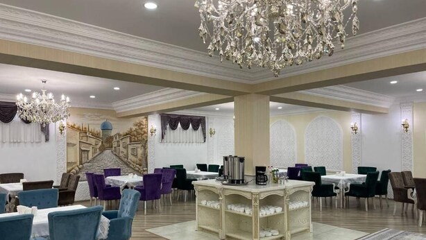 Un comedor espacioso con una mesa buffet central, elegantes candelabros y un mural en la pared.