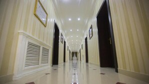 Un pasillo largo y bien iluminado con puertas a ambos lados, que conduce a un área central.