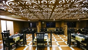 Een restaurant met een geruite vloer, zwarte stoelen en gedekte tafels.