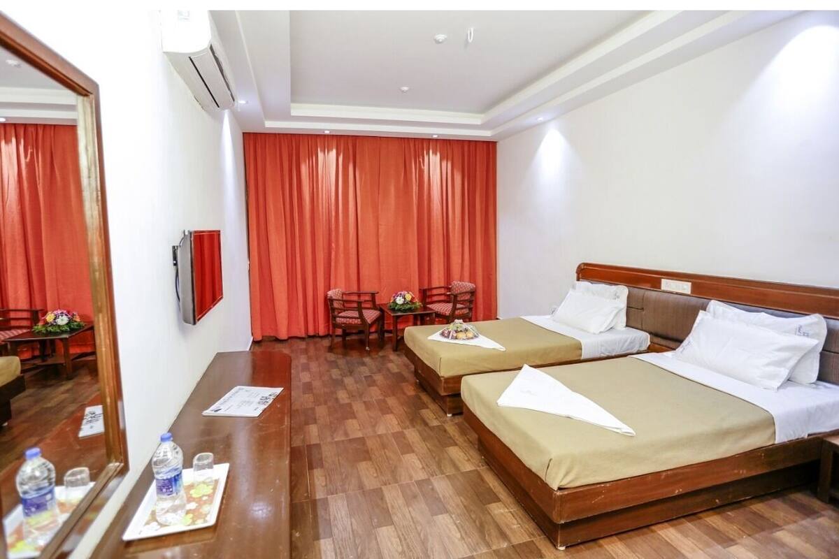 Habitació d'hotel amb dos llits, un sòl de fusta, escriptori amb cadira i un mirall.