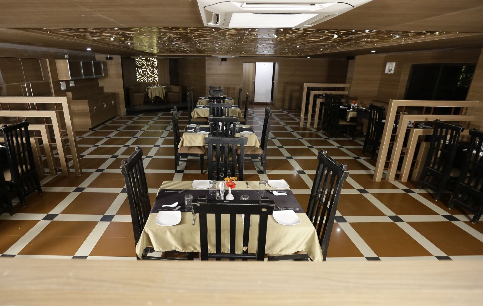 A restaurant with checkered flooring, multiple tables with chairs, and a central stage area.