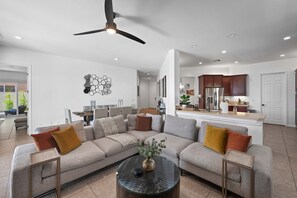 A spacious living room with a large sectional sofa, a coffee table, and a ceiling fan.