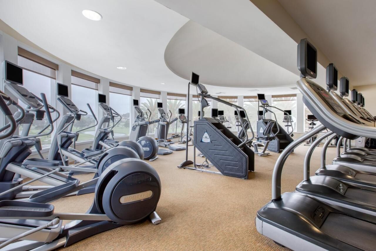 A gym with multiple treadmills, ellipticals, and weight machines.
