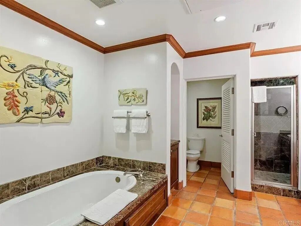 A bathroom with a large bathtub, a toilet, and a shower area.