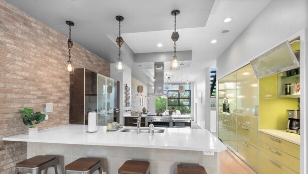 Una cocina moderna con una isla grande, taburetes de bar e iluminación colgante.