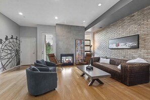 Un salon moderne avec une cheminée, des canapés en cuir et une grande fresque murale.