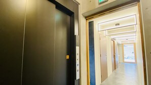 En gang med elevator, en dør med et rygeforbudsskilte, og et nødudgangsskilte.