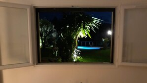 Une pièce avec une fenêtre donnant sur un jardin, de nuit.