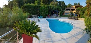 A swimming pool with a curved edge, surrounded by a paved deck. - Superb Apt 3p garden level villa with pool (La Roquette-sur-Siagne)