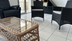 Ein modernes Wohnzimmer mit einem Glastisch, zwei schwarzen Sofas und einem Fernseher auf einem Schrank.