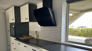 Eine moderne Küche mit weißen Schränken, einer schwarzen Arbeitsplatte und einem Fenster mit Blick auf einen Garten.