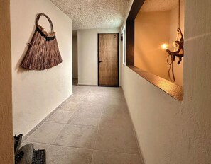 Stylish hallway with a numbered door, woven basket, and modern lighting.
