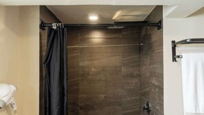 Ein Badezimmer mit Duschvorhang, Handtuchhalter und Fön.