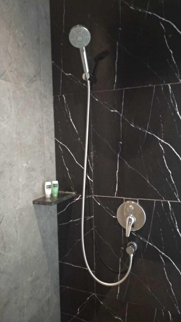 A shower with a handheld showerhead and a wall-mounted control valve.