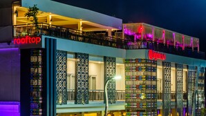 Un hotel de varios pisos con balcones, un bar en la azotea y un letrero que anuncia un centro de buceo.
