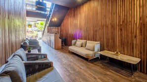 Un interior moderno con una recepción, paneles de madera, un sofá y una pequeña mesa.