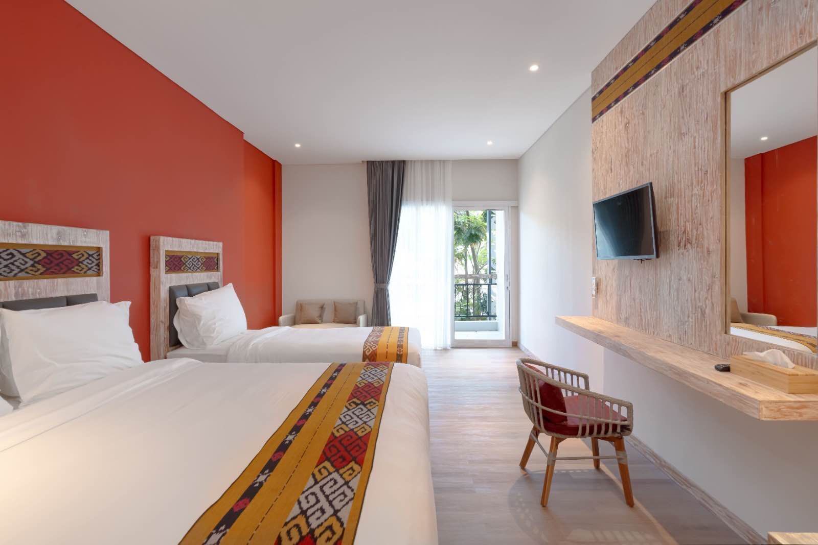 A hotel room with two beds, a TV, a chair, and a balcony with a view.