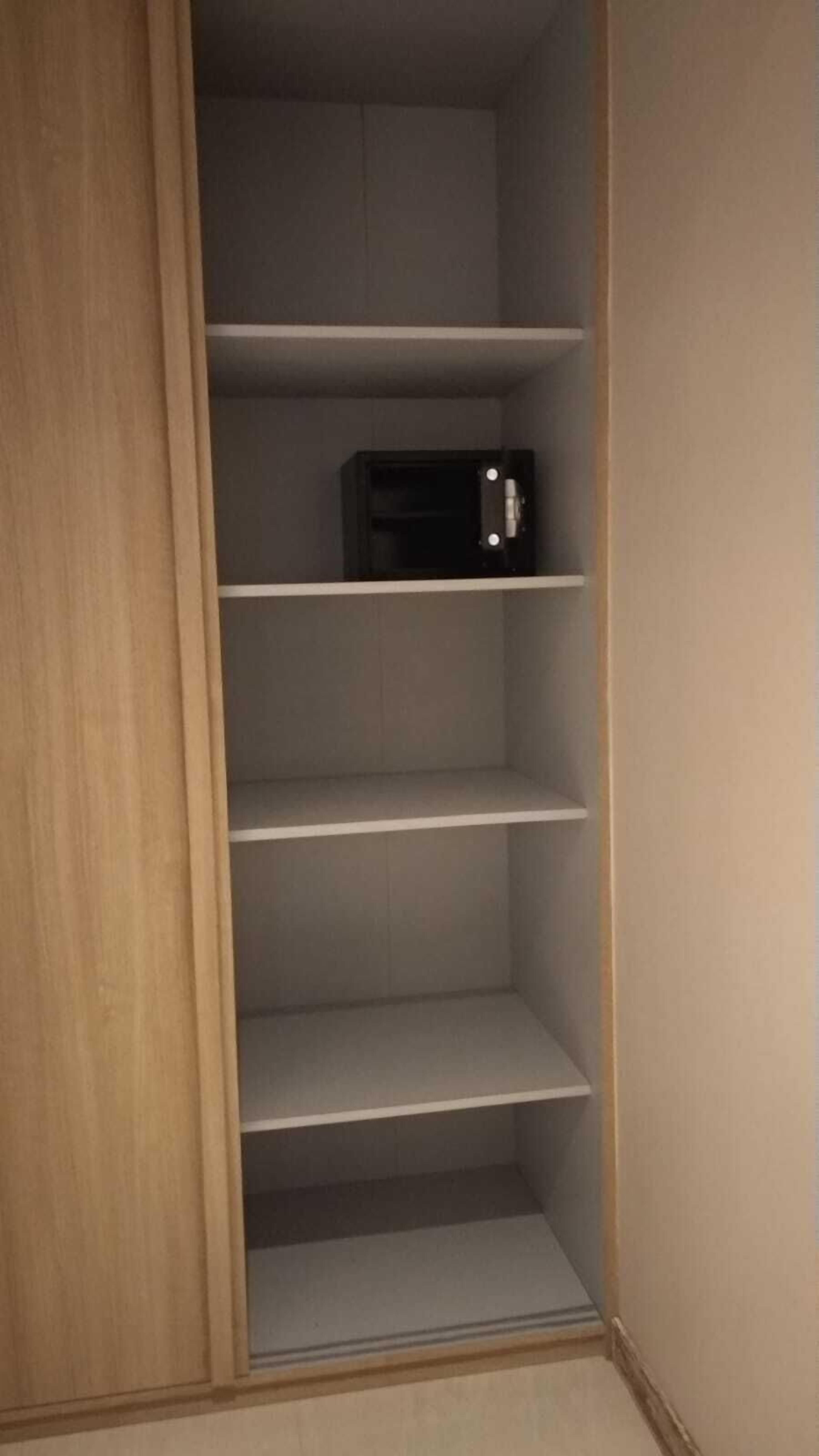 A closet with multiple shelves and a hanging rod, featuring a wooden door and a light-colored interior.