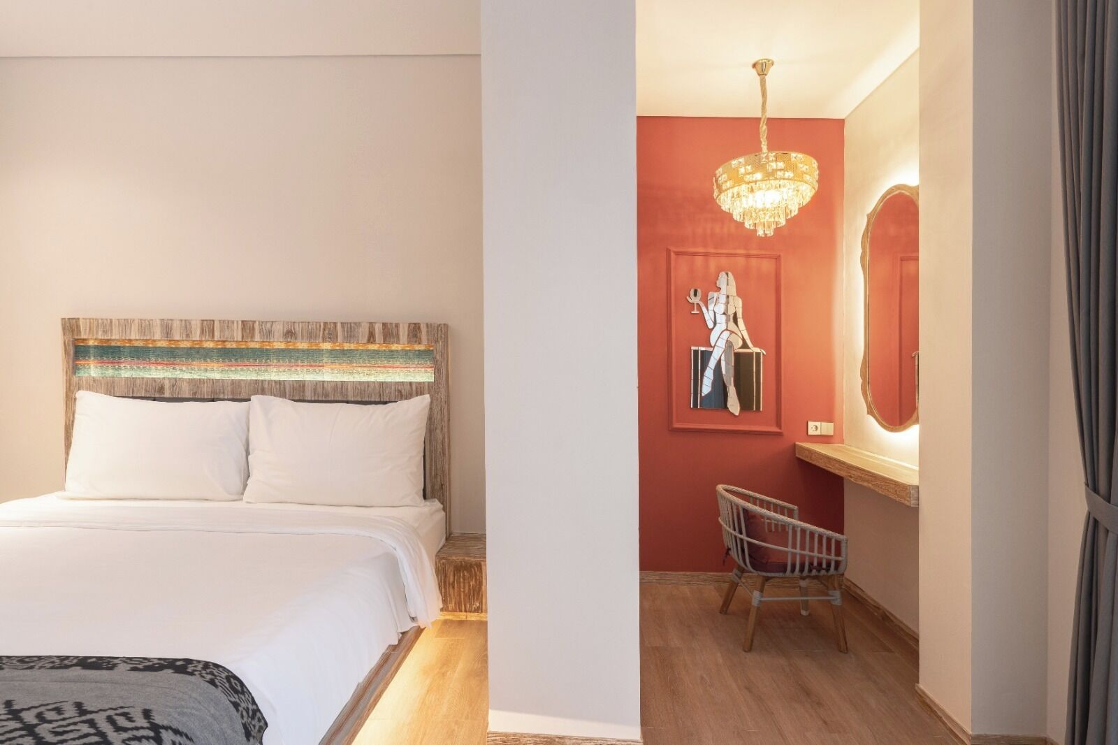A bedroom with a wooden headboard, a bed with white bedding, a nightstand, a chair, a mirror, and a chandelier.