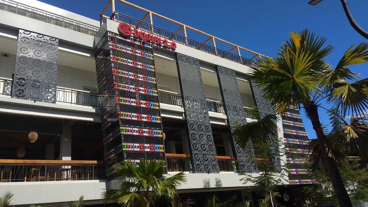 Un hôtel doté de nombreux balcons, d’un grand écran numérique et de palmiers.